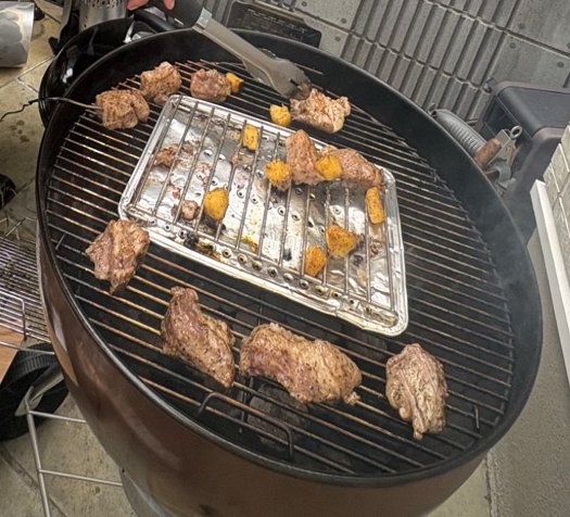 Weberの網の上で焼いている肉と、トレイの上の肉