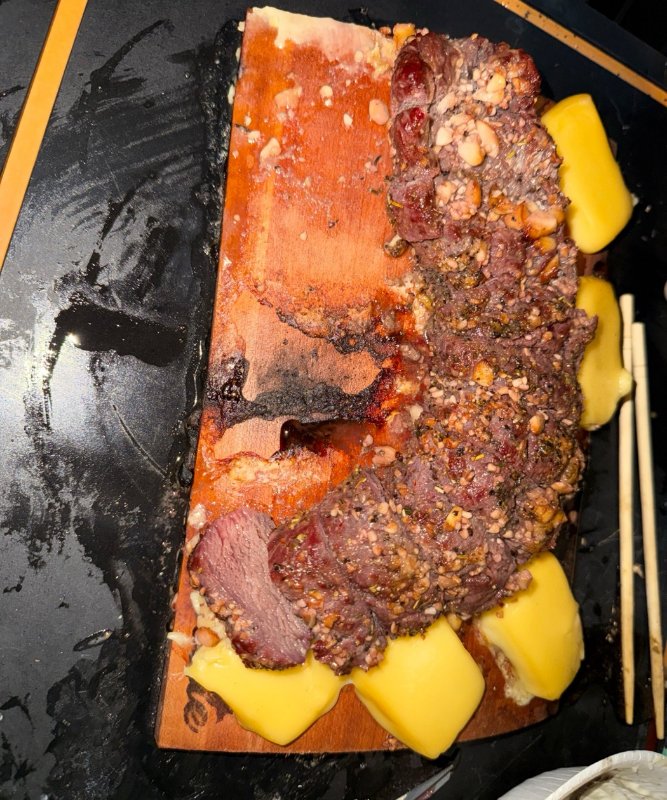 木の板の上の鹿肉とまわりに並べたチーズ